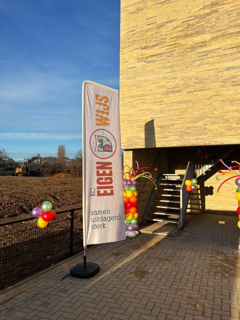 De Eigen-Wijs-vlag met het uilenlogo en de drie kernwaarden bij de entree van het kindcentrum